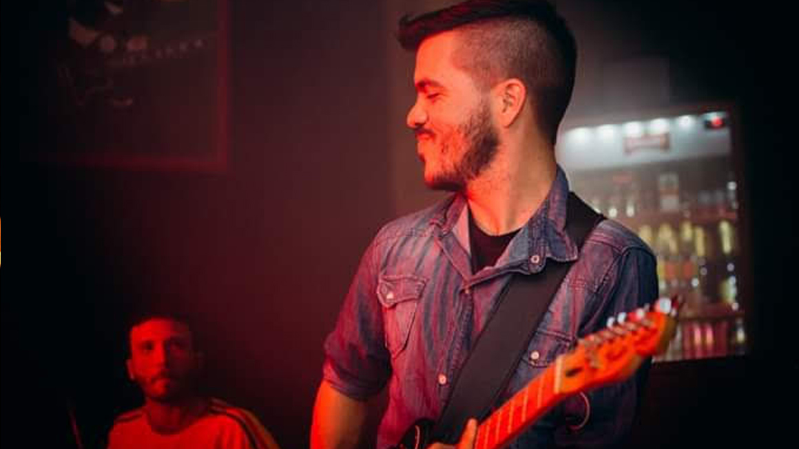 Simón Müller performing solo on guitar, captivating an audience with his eclectic mix of rock, Argentine folklore, and reggae. Book Now Through Originaria Events.
