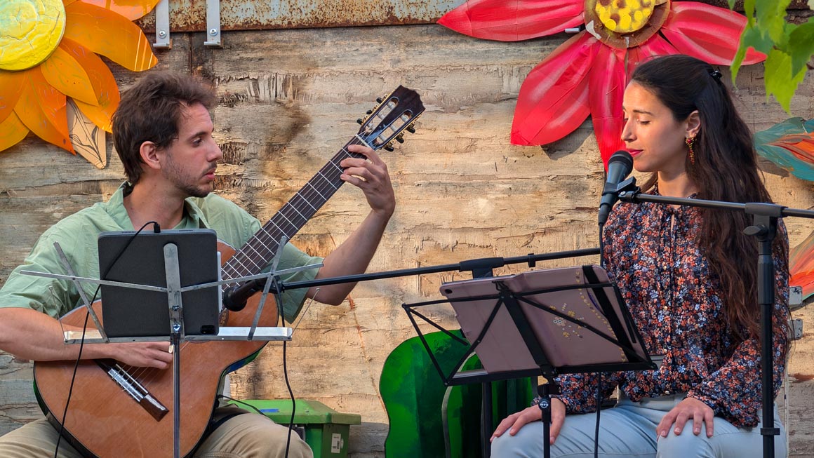 Dos Esquinas band members Maia Steinberg and Renzo Navone Rodríguez performing Argentine and Uruguayan folk music at an event, hosted by Originaria Events.